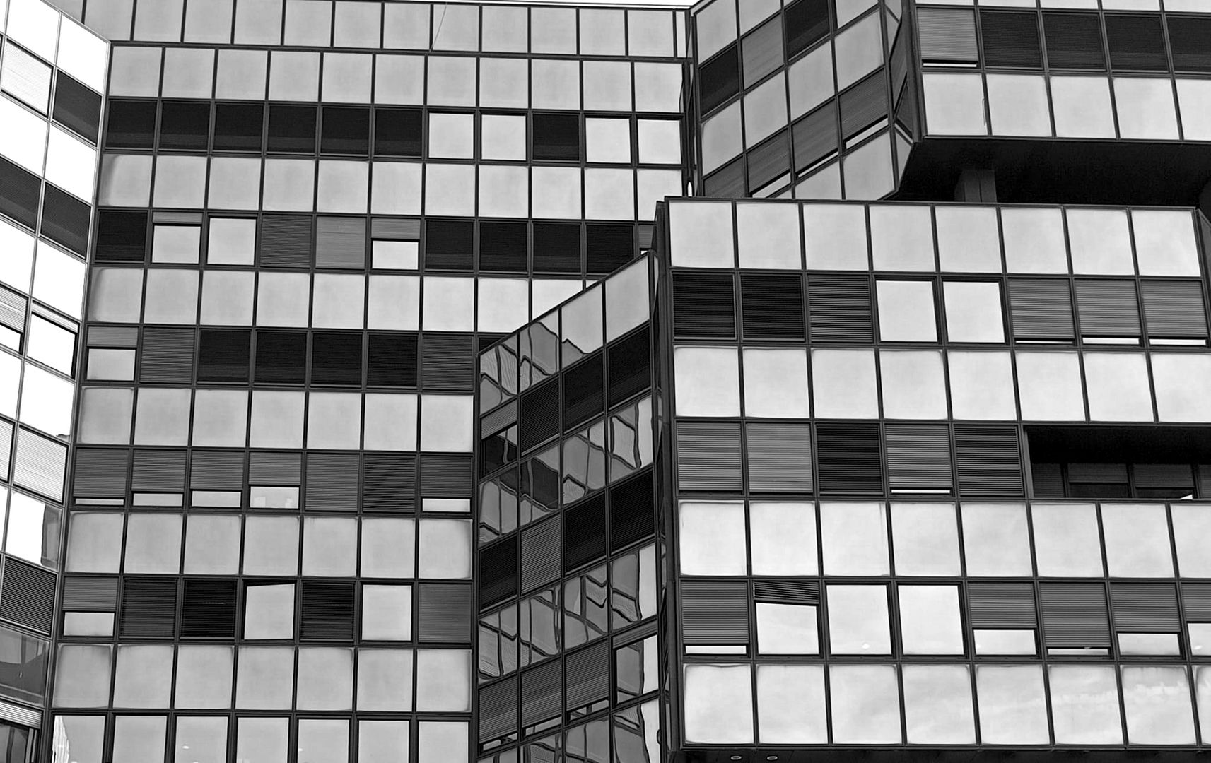 Black and white glass facade of a big building with lines of blinds down.